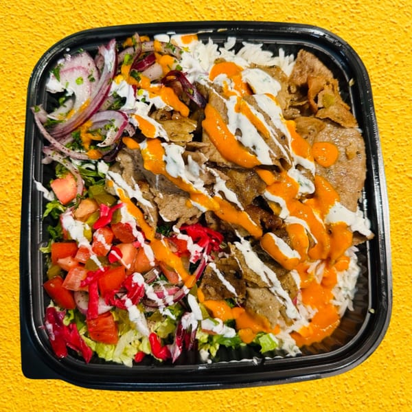 A BÖRO KABOB platter with rice, meat, salad, red onions, and orange and white sauces.